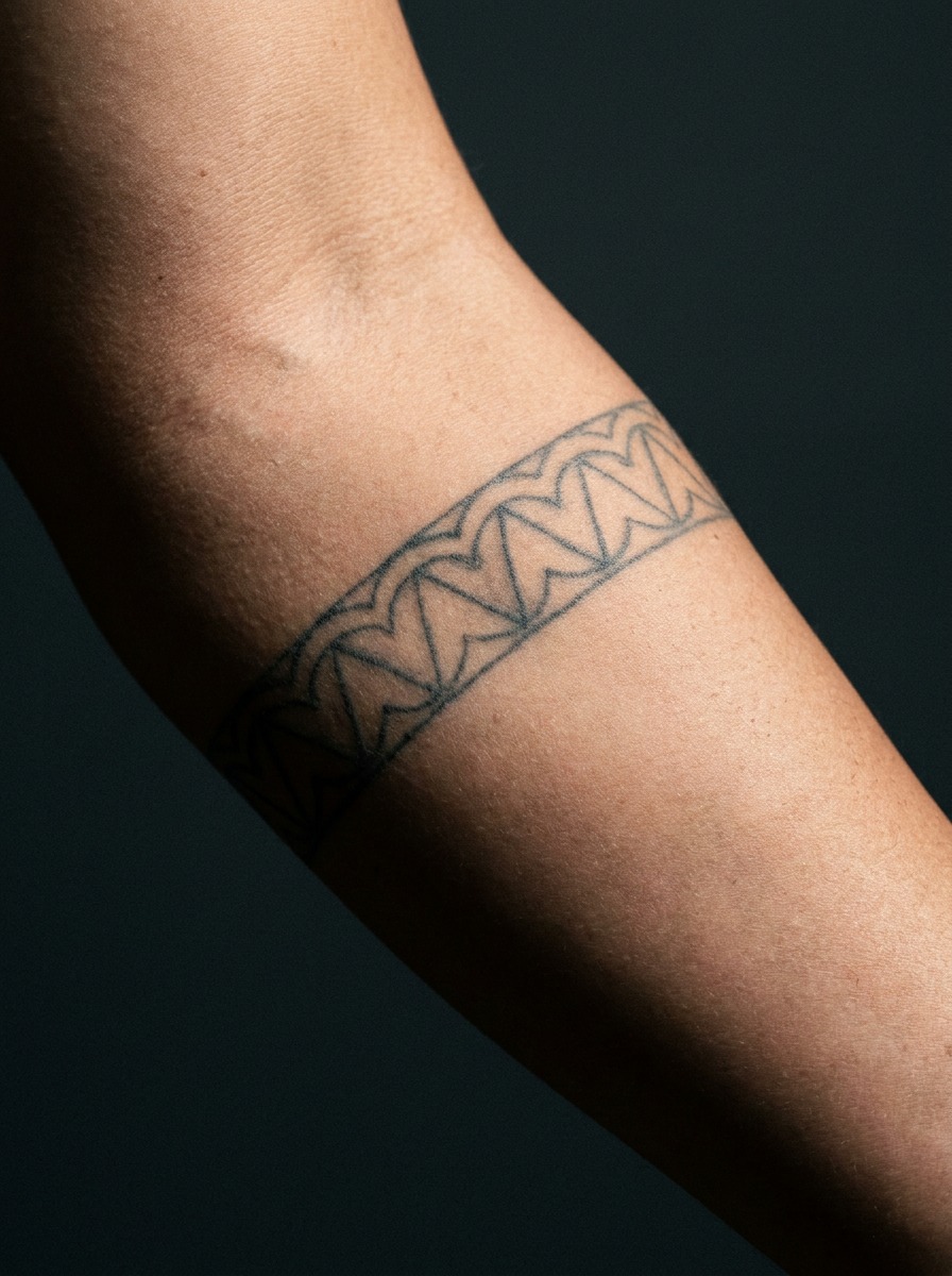 Outer forearm with a fine-line niho mano shark tooth pattern tattoo.