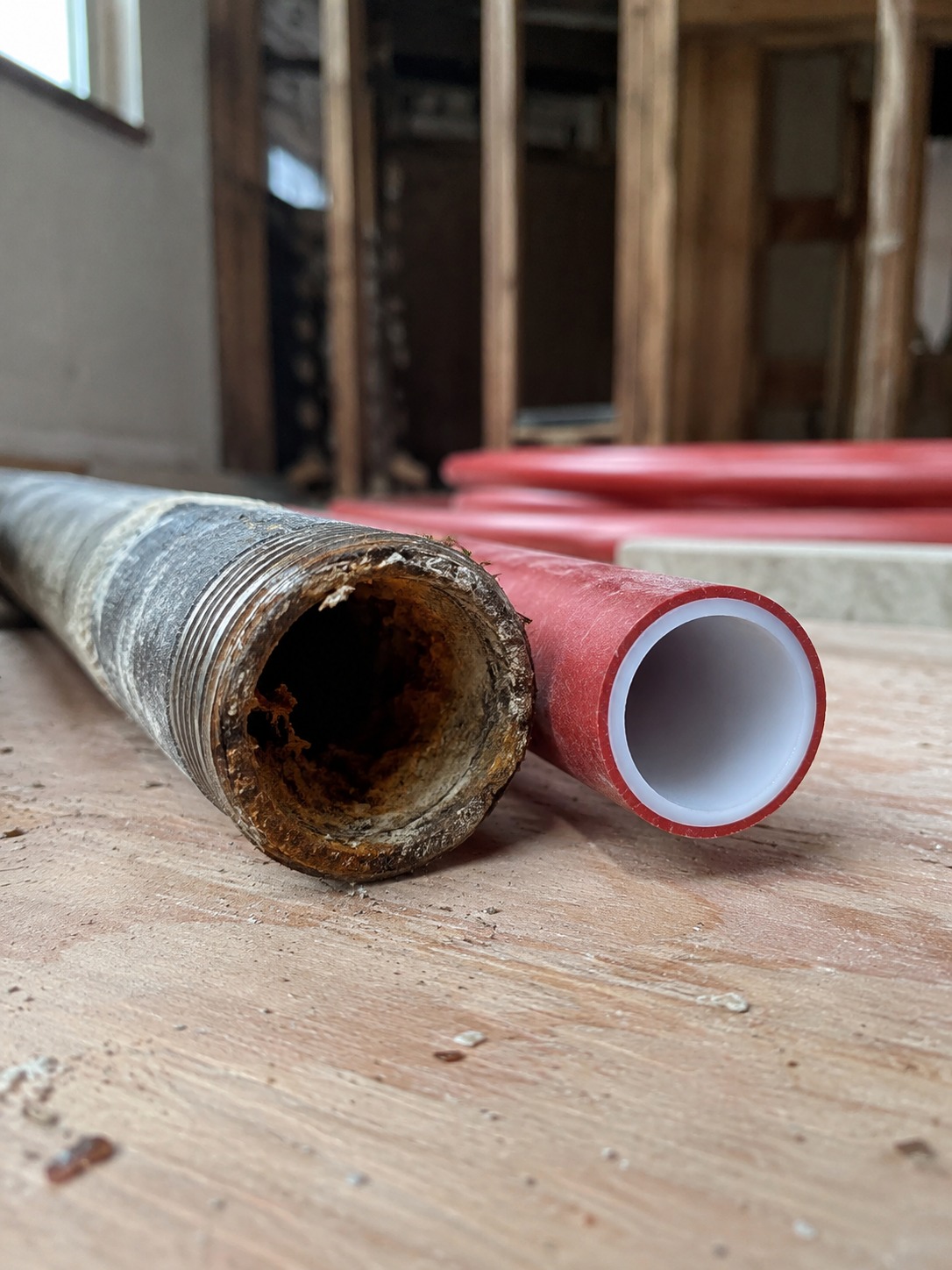 old galvanized pipe with corrosion placed beside new PEX piping