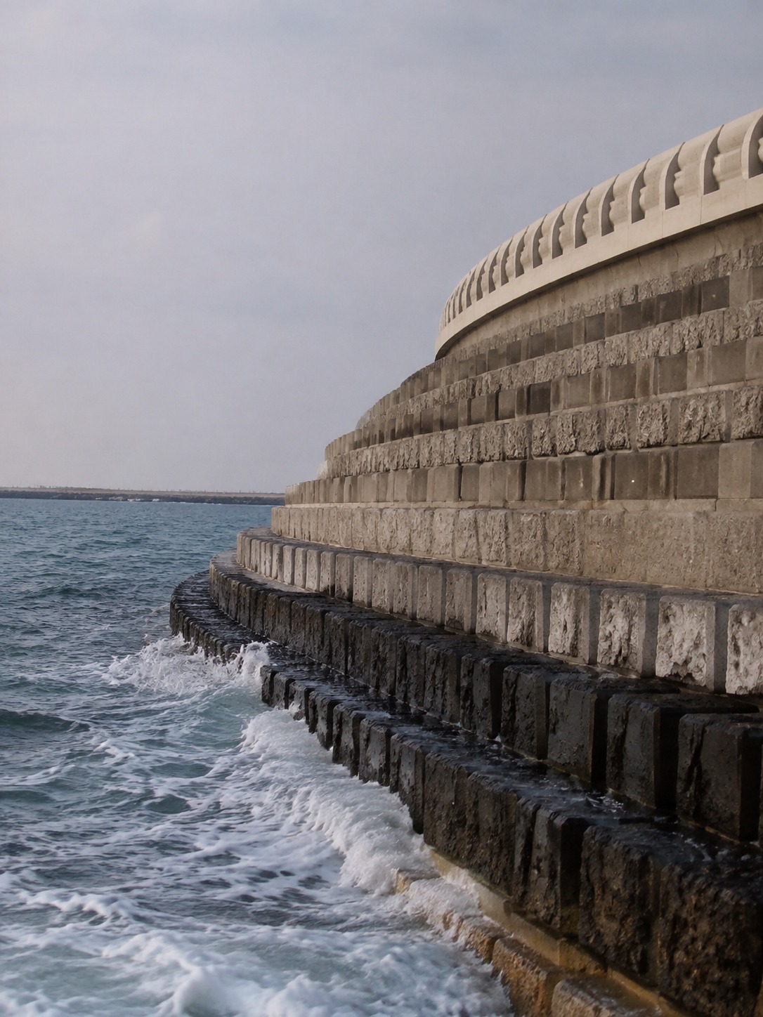 Engineered rock breakwater at Palm Jumeirah with waves breaking along the crescent.