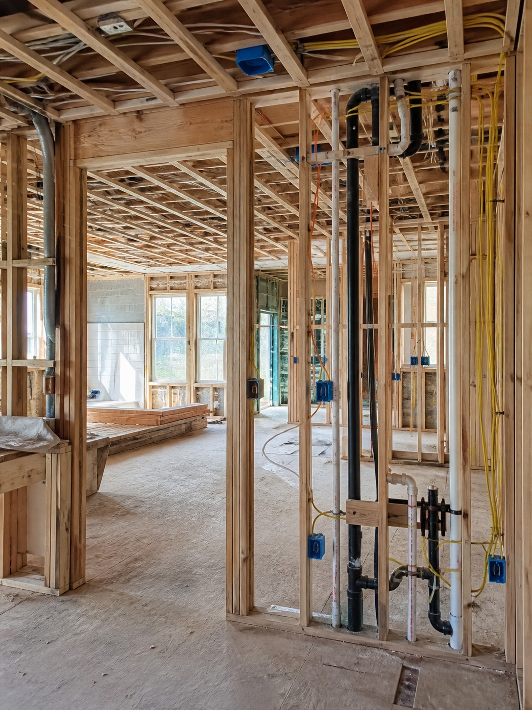renovation site with framing rough-in plumbing and electrical wiring visible before insulation