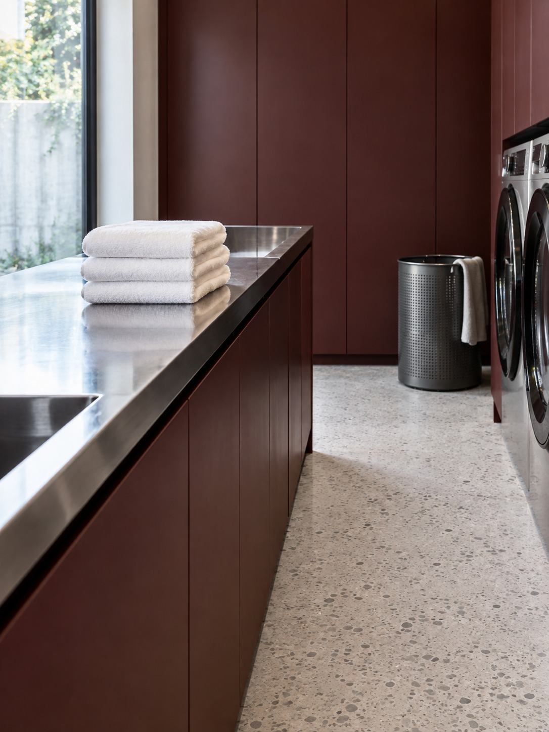 Separate folding and sorting zones White towels on a steel folding counter opposite a dark laundry hamper | Sky Rye Design White towels on a steel folding counter opposite a dark laundry hamper