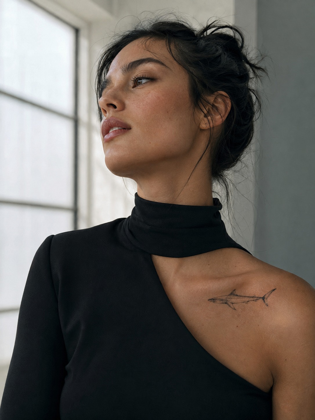 Model showing a fine-line mako shark tattoo along the collarbone with realistic healed ink and editorial lighting.