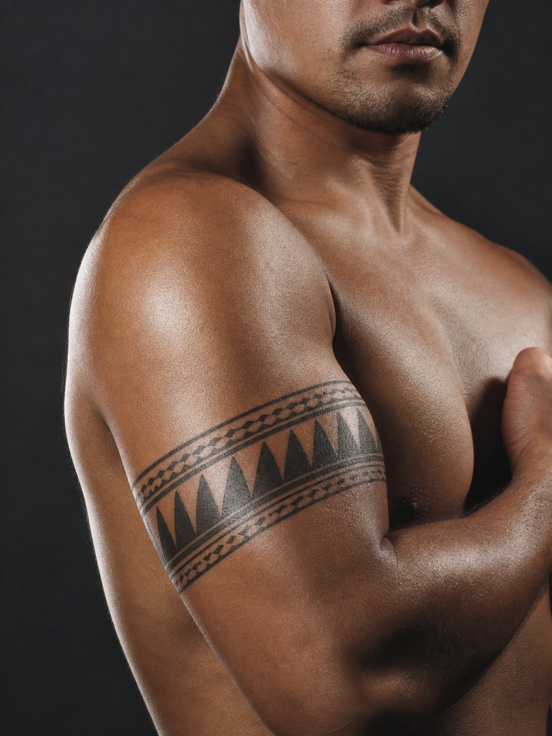 Model showing a tribal Polynesian niho mano shark-tooth tattoo wrapping the bicep with realistic healed ink and editorial lighting.
