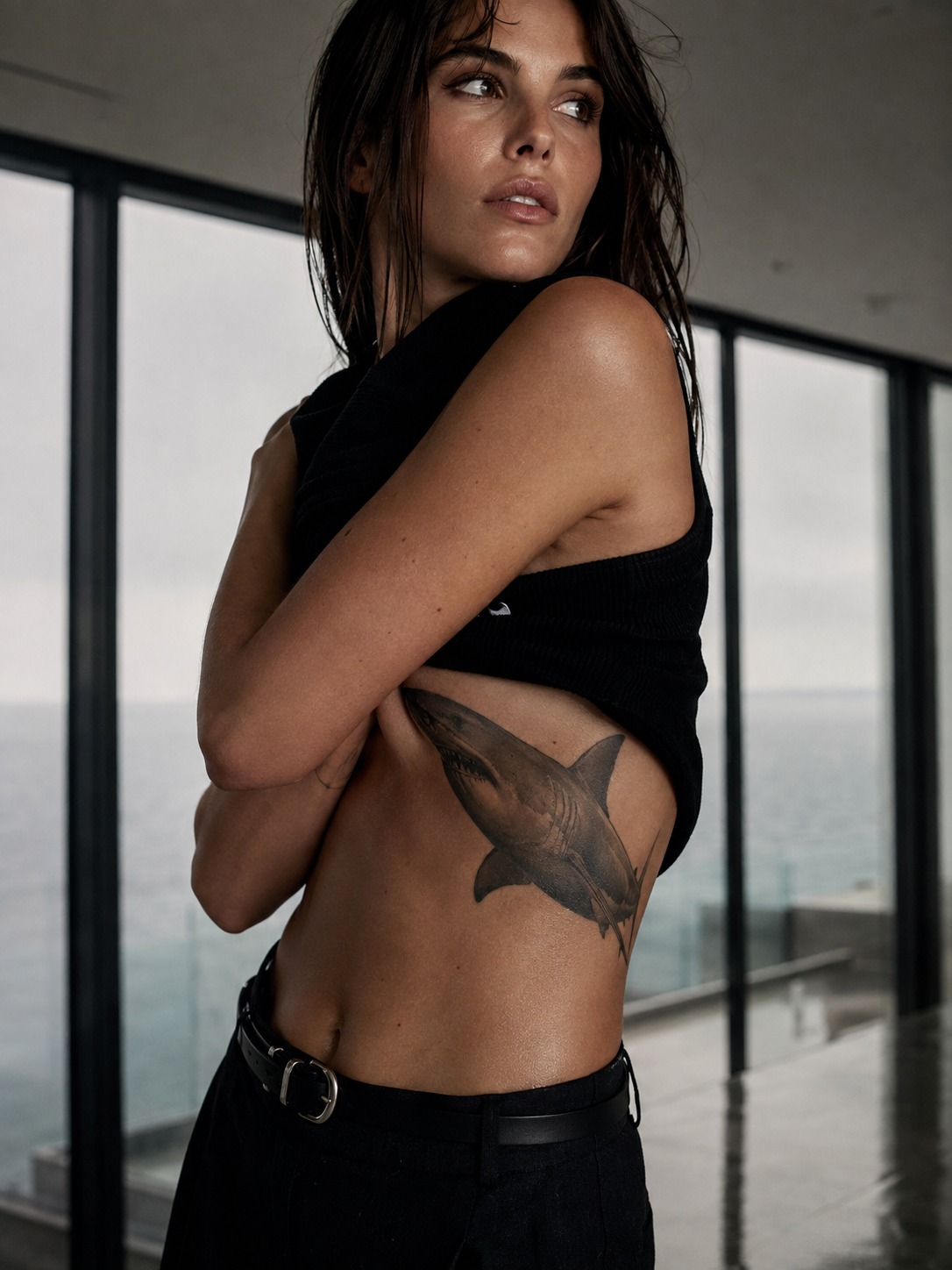 Model showing a realistic great white shark tattoo across the ribs with realistic healed ink and editorial lighting.