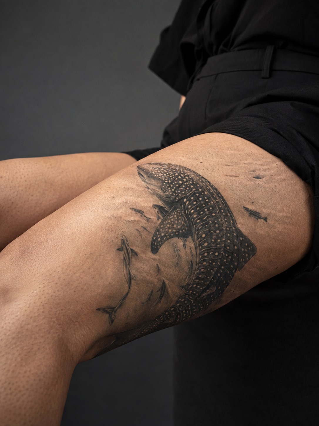 Model showing a large-scale realistic whale shark tattoo across the thigh with realistic healed ink and editorial lighting.