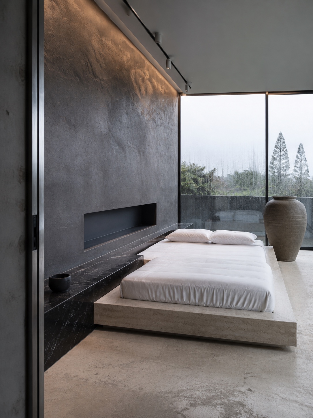 Ultra-modern charcoal mineral bedroom Gallery-like ultra-modern bedroom with a charcoal plaster wall, low stone platform bed, black marble ledge, and rainy glass backdrop. | Sky Rye Design Gallery-like ultra-modern bedroom with a charcoal plaster wall, low stone platform bed, black marble ledge, and rainy glass backdrop.
