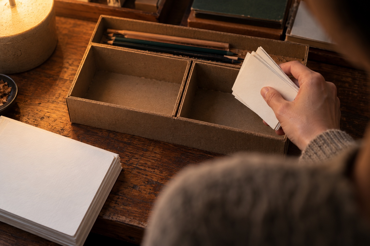 Packing without instructions A hand holding a card stack hesitates between two similar recesses in a cardboard game kit | Sky Rye Design A hand holding a card stack hesitates between two similar recesses in a cardboard game kit