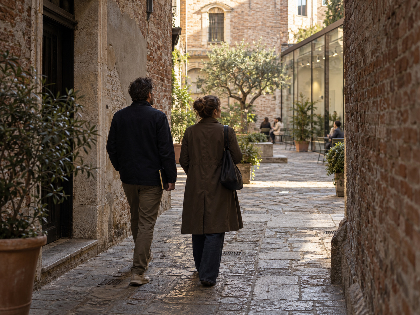Two walkers turning toward a small courtyard between old and new buildings