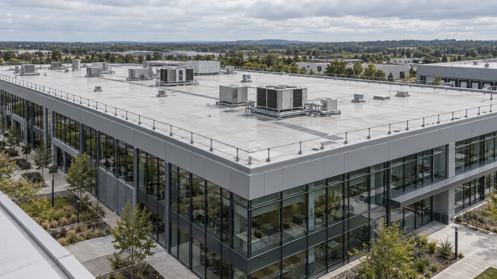 A large commercial roof managed as a building system Large contemporary commercial building with a clean, well-maintained low-slope white roof, neatly grouped rooftop equipment and a defined walkway under soft daylight | Sky Rye Design Large contemporary commercial building with a clean, well-maintained low-slope white roof, neatly grouped rooftop equipment and a defined walkway under soft daylight