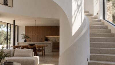 Curved white plaster wall wrapping around a staircase beside a tall window