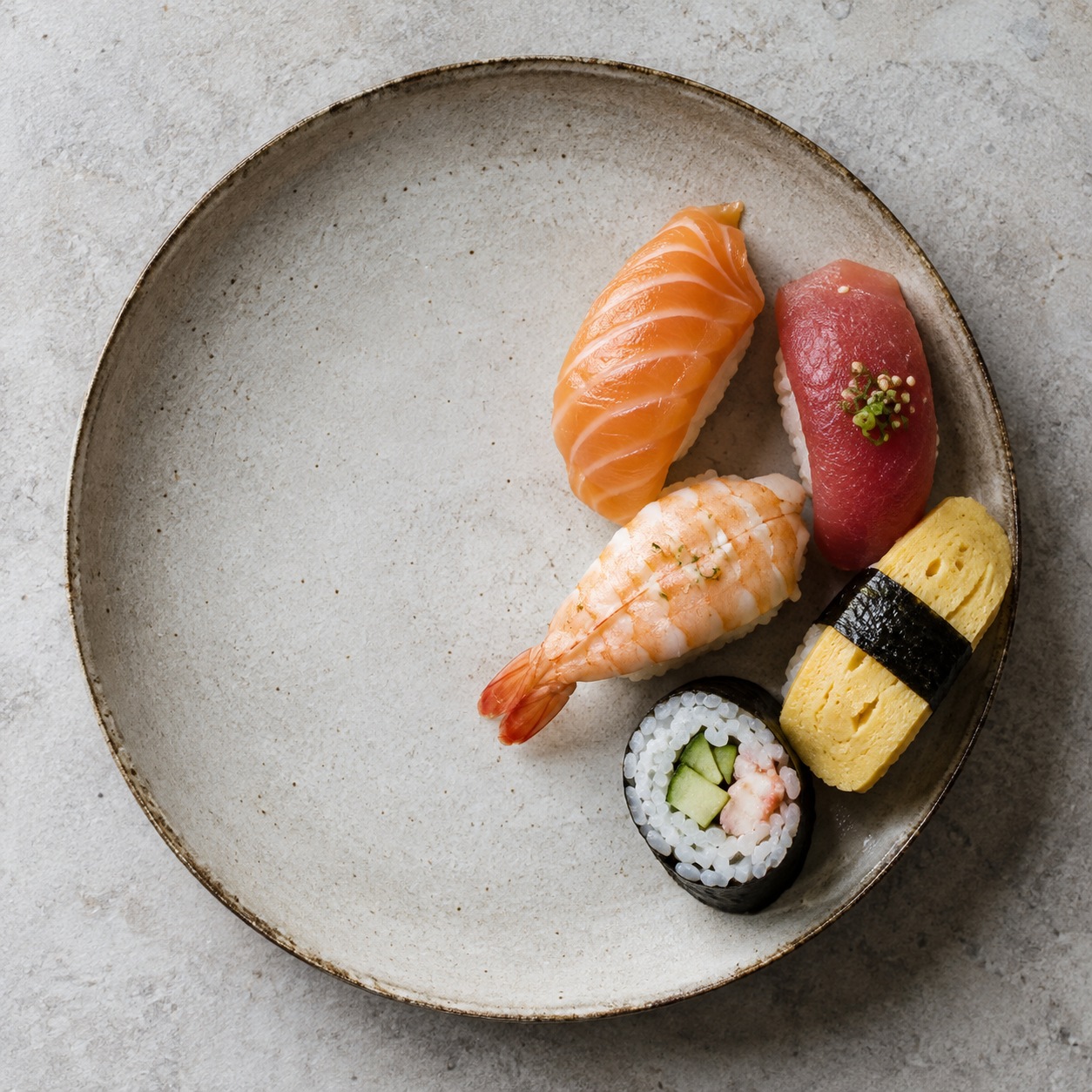 Top-down plate of five sushi pieces grouped with one third of the plate left empty