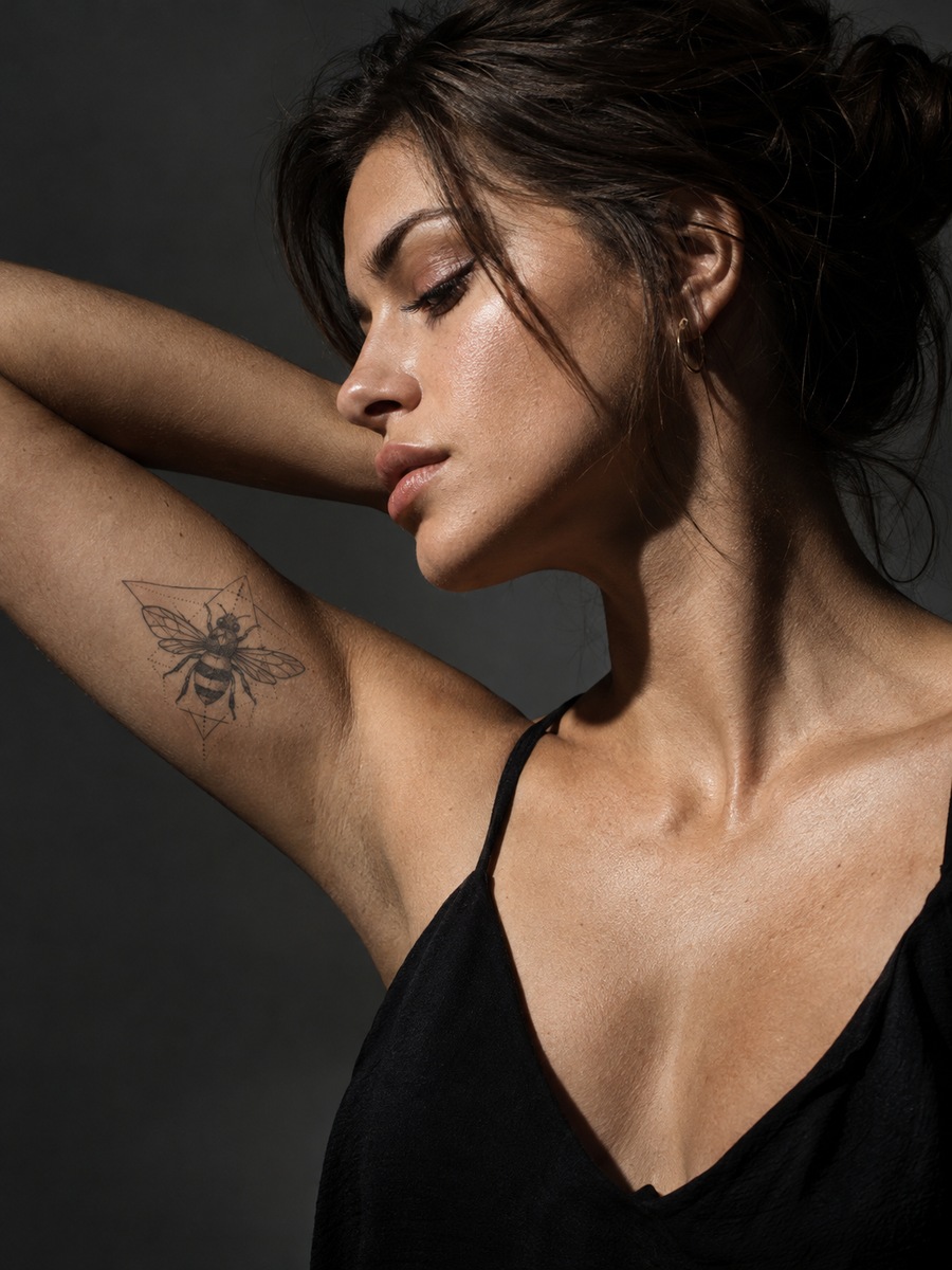 Geometric bee tattoo built from triangles on the inner bicep