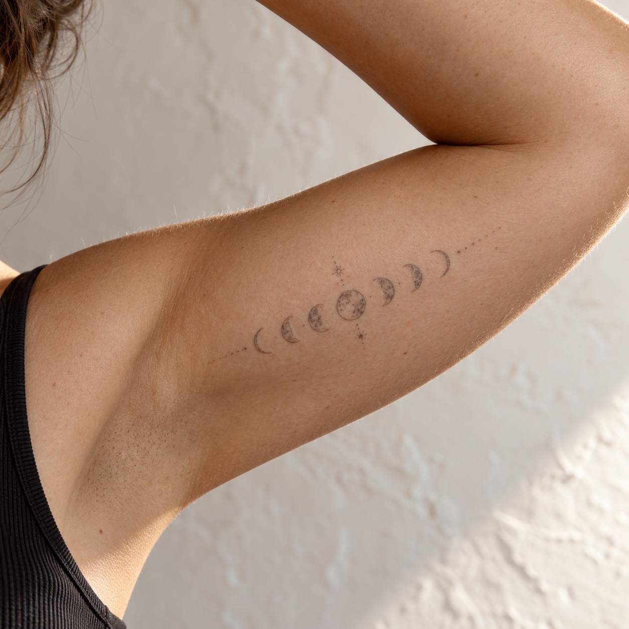 Moon phase tattoo on a raised inner upper arm