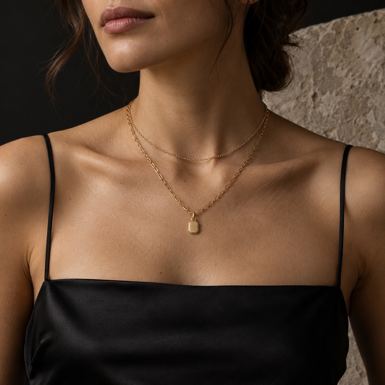 Layered gold-plated necklaces with clear spacing Two gold-plated necklaces at distinct lengths above a black silk neckline, including one small geometric pendant. | Sky Rye Design Two gold-plated necklaces at distinct lengths above a black silk neckline, including one small geometric pendant.