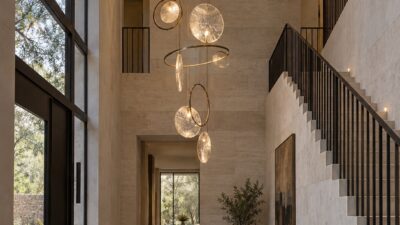Long sculptural chandelier filling the vertical space of a modern high-ceiling foyer